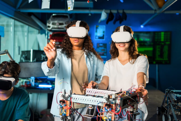 Two young women in VR glasses doing experiments in robotics in a laboratory. Robot on the table